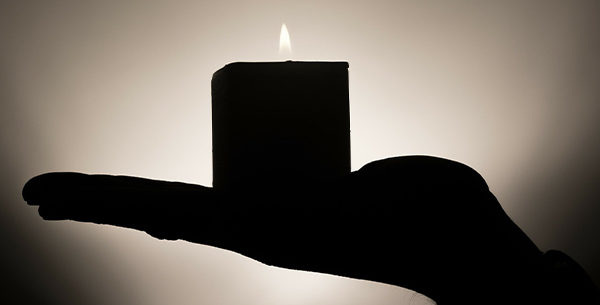 Person holding a lit candle in a dark room